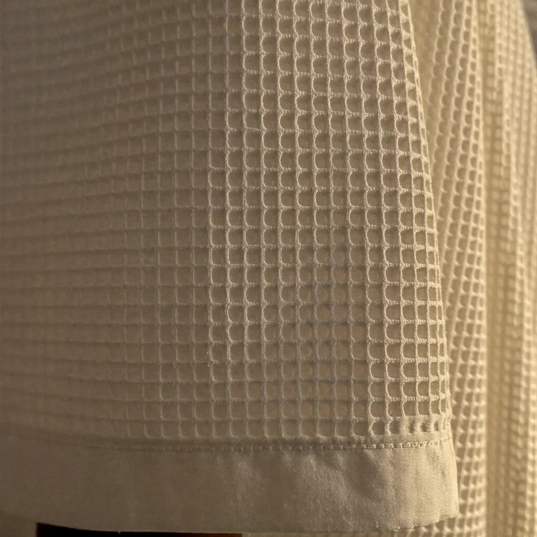 Close-up of off-white cotton waffle weave and a stitched hem